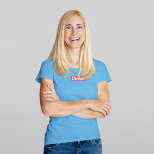 smiling blonde woman wearing a light blue dinker pickleball shirt apparel supreme inspired front view