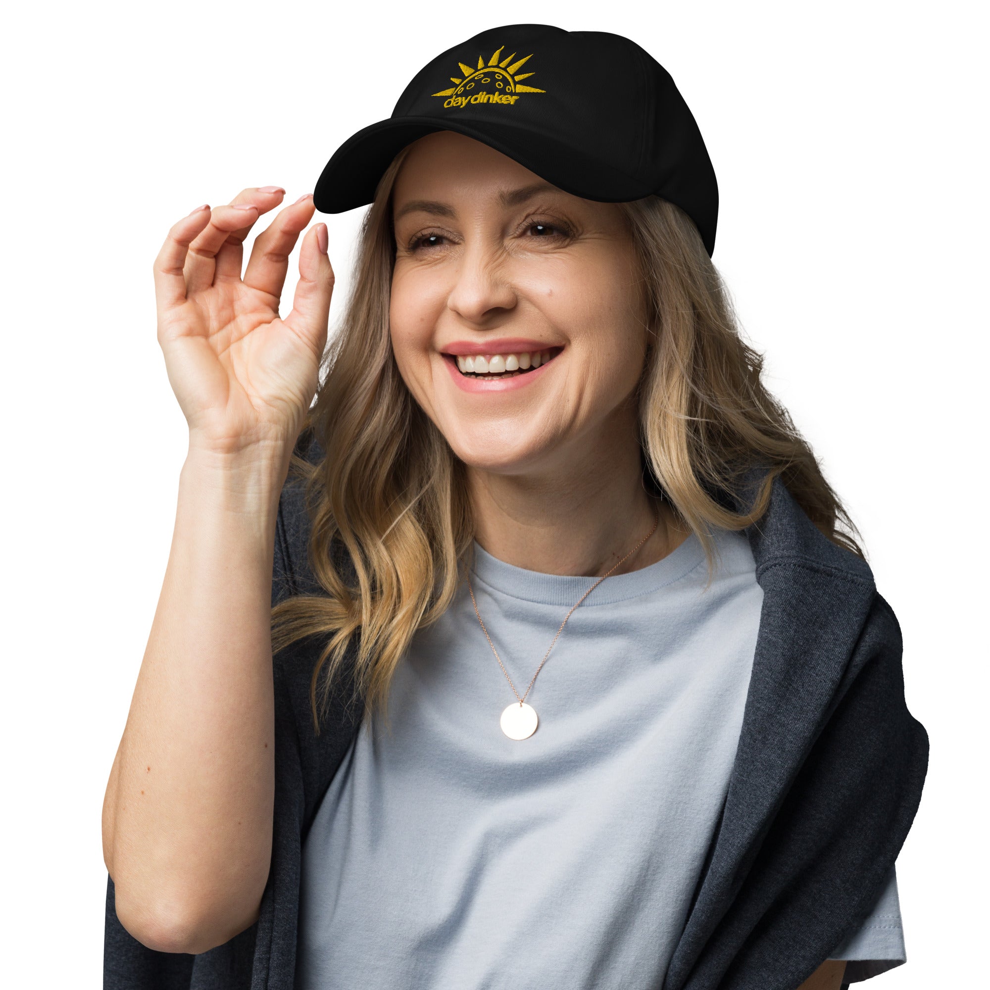 smiling blonde woman wearing black embroidered day dinker pickleball dad hat with pickleball sun pattern yellow on black
