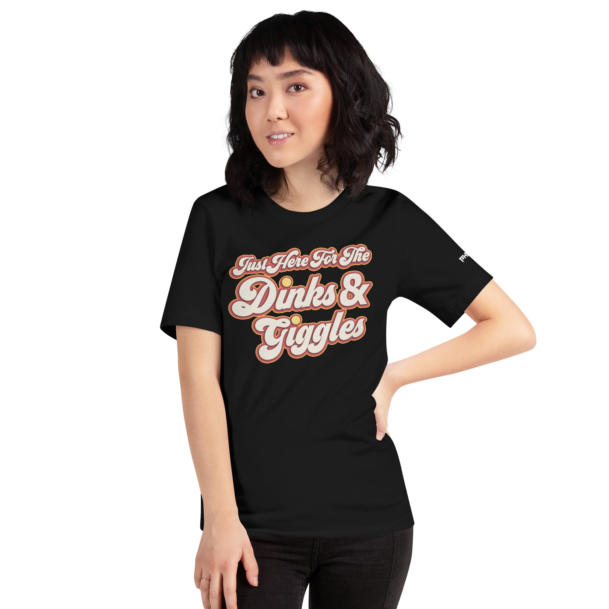 smiling petite asian woman wearing black just here for the dinks and giggles pickleball shirt apparel front view