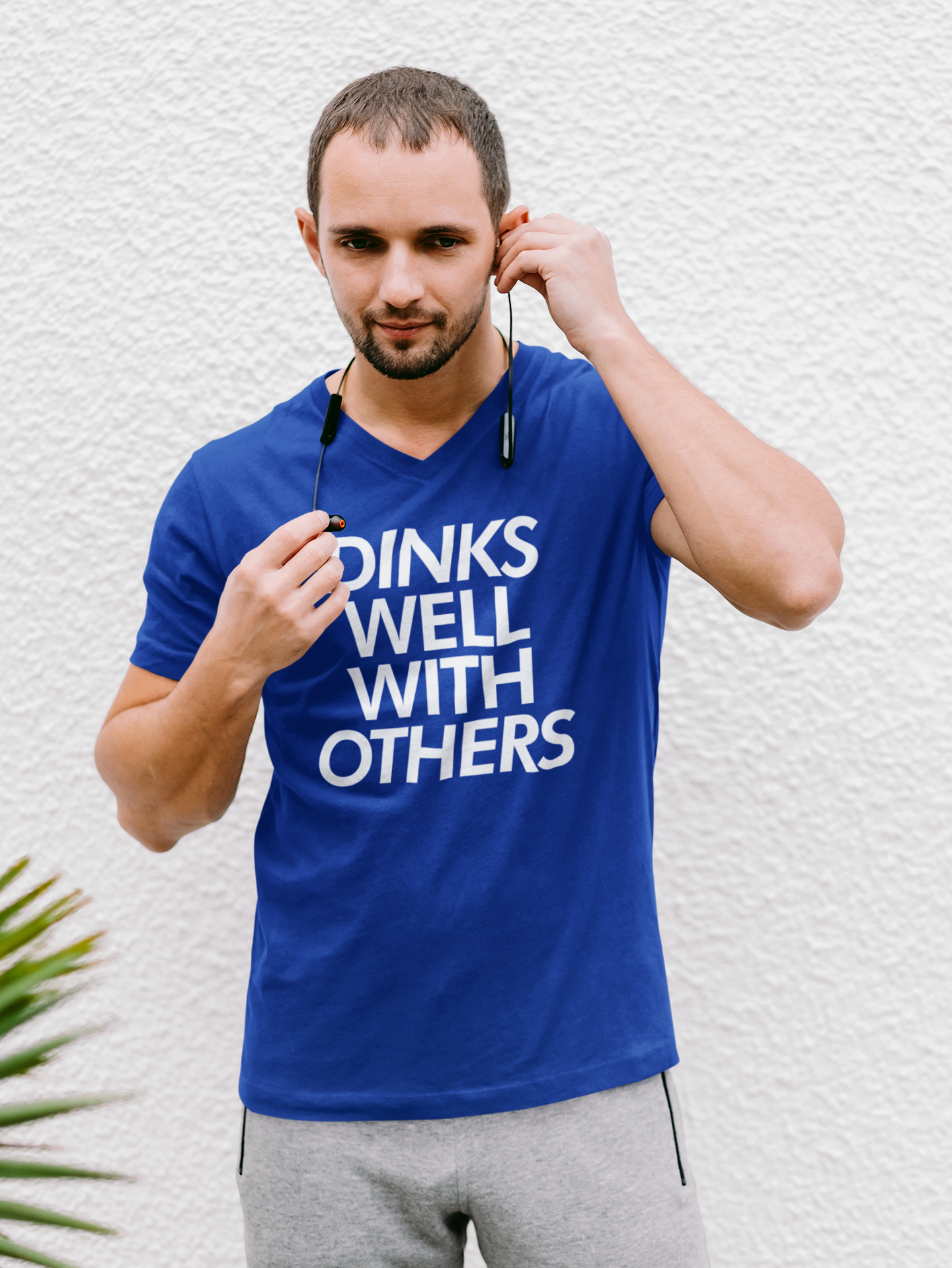 man with headphones wearing a royal blue dinks well with others pickleball shirt apparel front view
